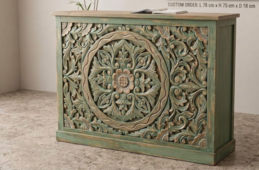 A carved wooden reception desk or cabinet with a distressed green finish and ornate floral detailing, shown in a room setting with a text overlay indicating custom order dimensions.